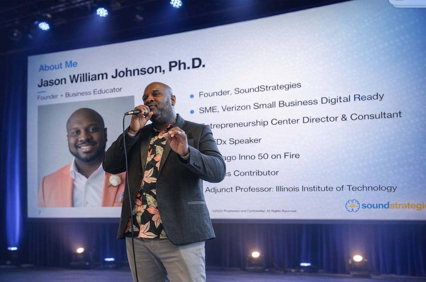 Dr. Jason William Johnson on stage with microphone, SoundStrategies presentation behind him